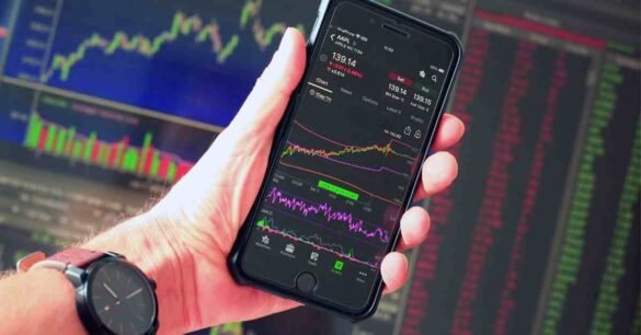 Person analyzing stock market data on smartphone with trading charts and price trends displayed